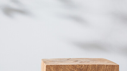 Wooden cubic podium on a white background with leaves shadow