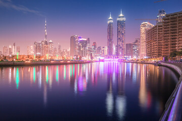 Dubai water canal promenade at night with illuminated skyscrapers. UAE landmarks and destinations