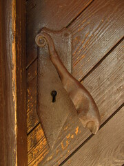 Stara metalowa klamka w drewnianych drzwiach, Polska