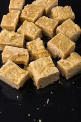 potato milk toffee or potato fudge, sweet candy on a reflective black surface