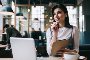 Pensive woman with clipboard in cafe