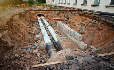 Heating pipeline in trench, repair of city communications, replacement of old pipes. Replace water pipes, heating main repair and renovation. Hot and cold water pipe excavated by tractor. - obrazy, fototapety, plakaty