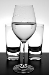wineglass filed with water and two tequila glasses in black and white
