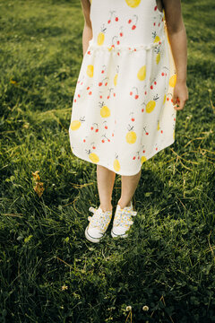 Little girl in summer dress standing on green grass
