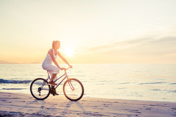 Fototapeta premium Beautiful woman rides a bicycle by the sea