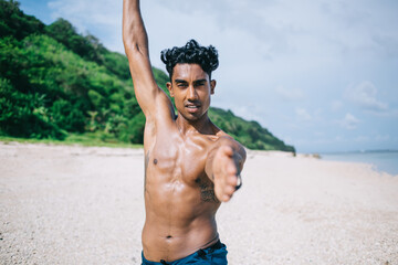 Fototapeta na wymiar Adult ethnic athlete training on ocean shore during sunny day