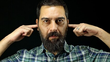 Annoyed bearded man covering his ears with fingers. 