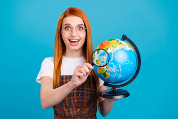 Photo of young school girl happy positive smile hold loupe enlarge globe world planet isolated over blue color background