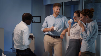 Naklejka premium Young multiethnic coworkers having fun conversation during coffee break in modern office