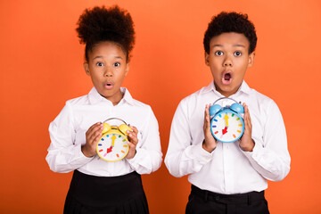 Photo of two young black kids amazed shock hold timer late missed lesson isolated over orange color background