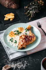 Roasted Chicken thighs with rice, pineapple on a wooden board