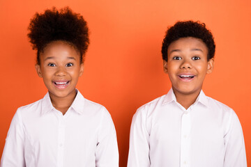 Photo of two young black kids amazed shocked omg fake novelty news isolated over orange color background