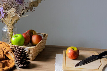 Cut red apple on a cutting board and some apples on a basket. Autumn composition. Cosy concept. Blog, blogger and social media.