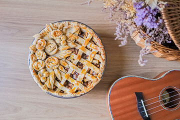 Pretty and Styled apple pie with flowers and leafs on it. Picnic basket with dried flowers and ukulele.