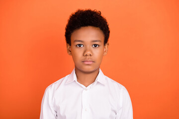 Photo of young african boy serious confident pupil clever education isolated over orange color background