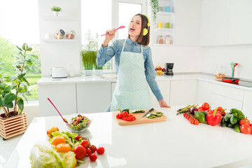 Portrait of attractive cheerful girl preparing meal singing hit having fun at home light white kitchen indoors