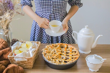 Decorated apple pie on a wooden table and a tea pot and cup of tea. Afternoon tea concept.