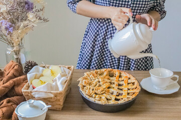 Autumn composition. Decorated apple pie, tea pot and a cup of tea on a wooden table. Afternoon tea concept.