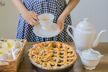 Autumn composition. Decorated apple pie, tea pot and a cup of tea on a wooden table. Afternoon tea concept.