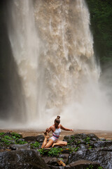 Fototapeta na wymiar Beautiful woman doing yoga near a waterfall in Bali