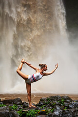 Obraz na płótnie Canvas Beautiful woman doing yoga near a waterfall in Bali