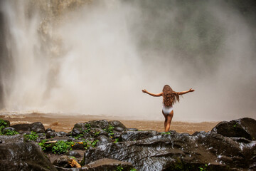 Fototapeta na wymiar Beautiful woman near a waterfall in Bali