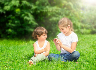 Naklejka na ściany i meble children sit on the grass outdoors and smile