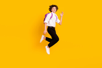 Fototapeta na wymiar Full length profile photo of funny small brunet boy jump wear bag uniform shoes isolated on yellow background