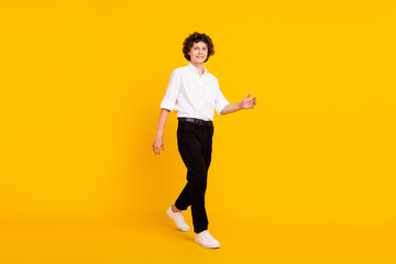 Fototapeta na wymiar Full size photo of optimistic small brunet boy go wear white shirt trousers shoes isolated on yellow background