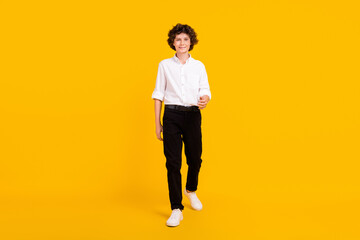 Fototapeta na wymiar Full body photo of nice little brunet boy go wear white shirt trousers shoes isolated on yellow background
