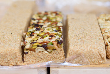 Sweet halva, dessert from sesame seeds with nuts on the board in the market. Selective focus.