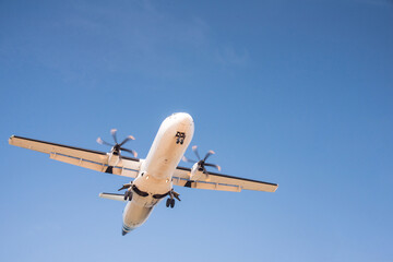 Passenger commercial airplane landing against blue cloudy sky.