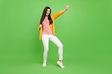 Fototapeta na wymiar Full length photo of joyful brown hairdo young lady hands fists wear yellow shirt trousers isolated on green color background