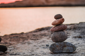 Pyramid stones balance on the sand of the beach. The object is in focus,sunset view.
