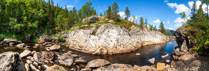 Summer background panorama with view on bend of the river among rocks and taiga forest. Boulders Of Pebbles And Cobblestones In Riverbed. Norway.