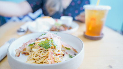Pasta Carbonara. Spaghetti with bacon, parsel and parmesan cheese. Pasta Carbonara on white plate with parmesan on dark background. Italian food concept.