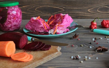 Sauerkraut with beetroot on a platter and in a jar on a wooden background.