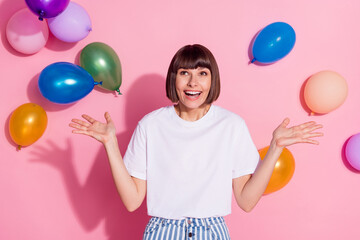 Portrait of attractive amazed cheerful girl having fun weekend good mood air balls flying isolated over pink pastel color background