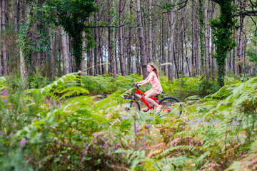 cute little girl riding a bicycle in the forest