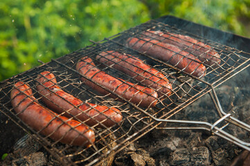 BBQ sausages cooking on outdoor grille, smoke and flames grillin