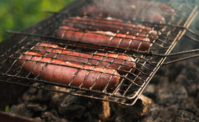 BBQ sausages cooking on outdoor grille, smoke and flames grillin