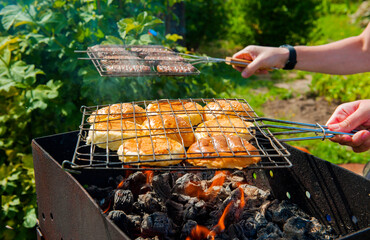 Meat cutlets and buns for burger on the grill in the fire. Outdoor cooking