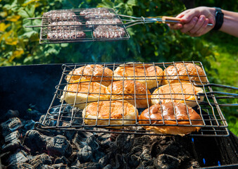 Meat cutlets and buns for burger on the grill in the fire. Outdoor cooking