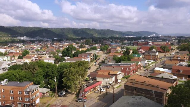 A morning forward aerial view of Ambridge, a small working class river town in Western Pennsylvania. Bridge over the Ohio River in the distance. Pittsburgh suburbs.  	