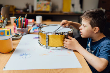 Autistic, Autism or Down Syndrome children boy is playing baraban in art classroom. Concept...