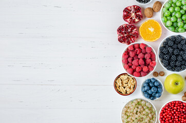 Fresh berries, fruits, nuts on a white wooden background. The concept of healthy eating. Food contains vitamins and trace elements. Copy space.