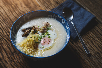 Rice porridge in bowl on wooden plate.