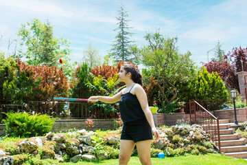 young Teenage girl plays with tennis racket and ball in the garden