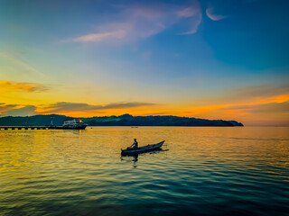 Silhouette of a fisherman in boat at beautiful sunset