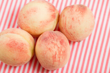 Ripe pink peaches on a striped summer tablecloth. Delicate velvety and juicy peaches